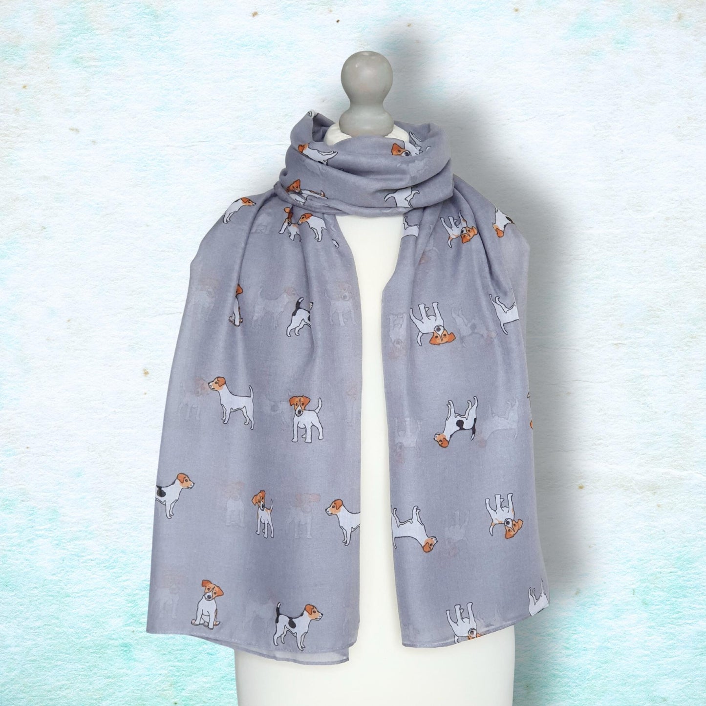 Grey scarf with jack russell dog pattern on a mannequin against a light blue background