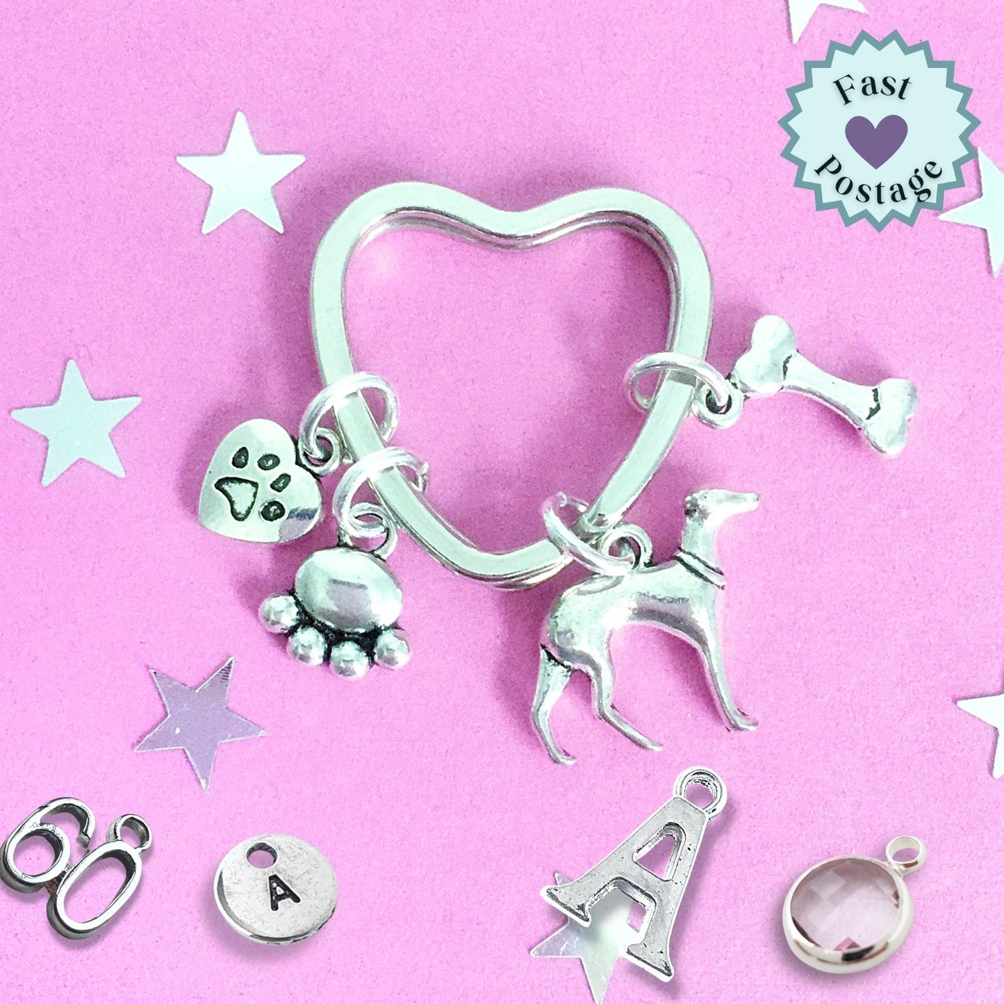 Silver keychain with dog and paw print charms on a pink background with stars