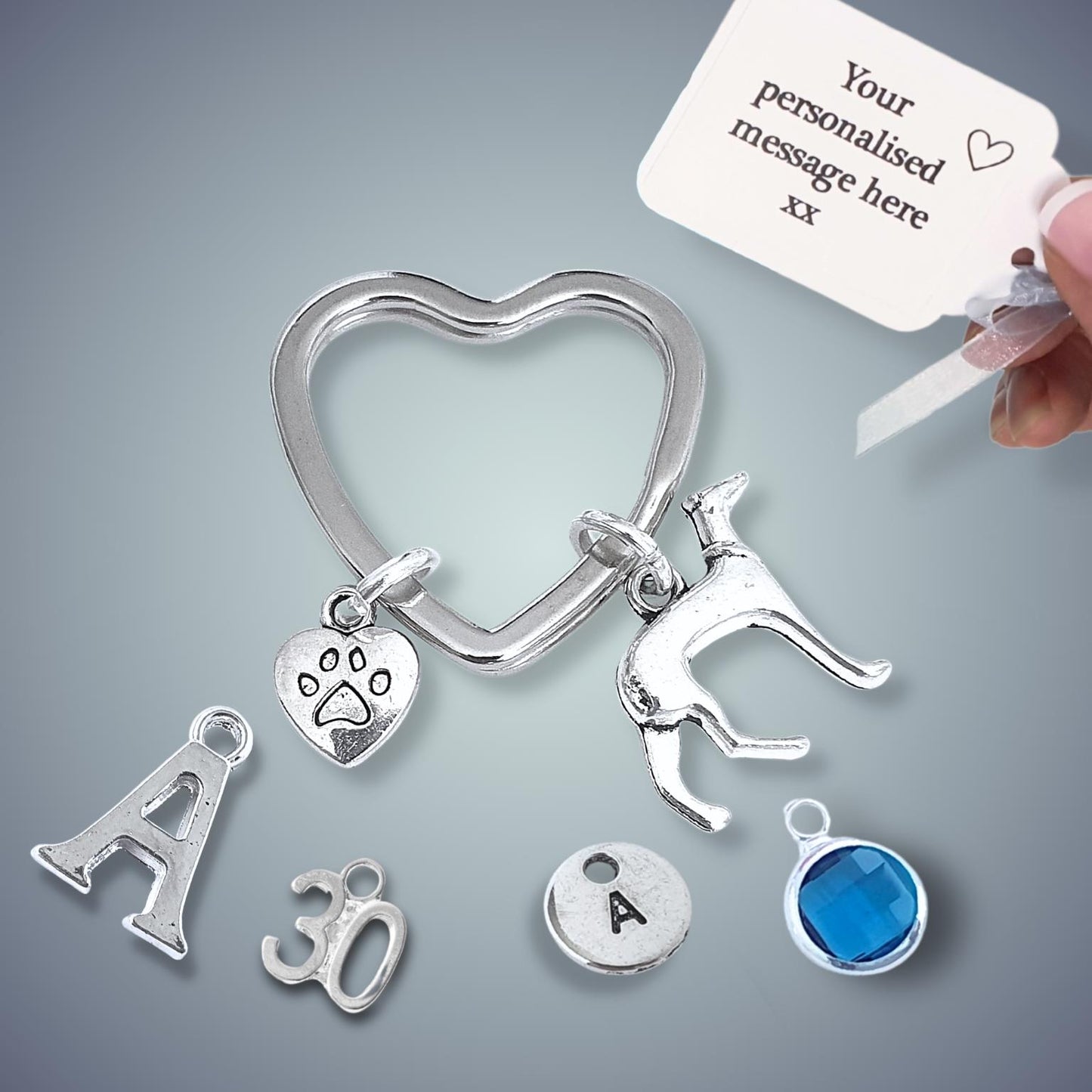Silver heart-shaped keychain with various charms on a gray background