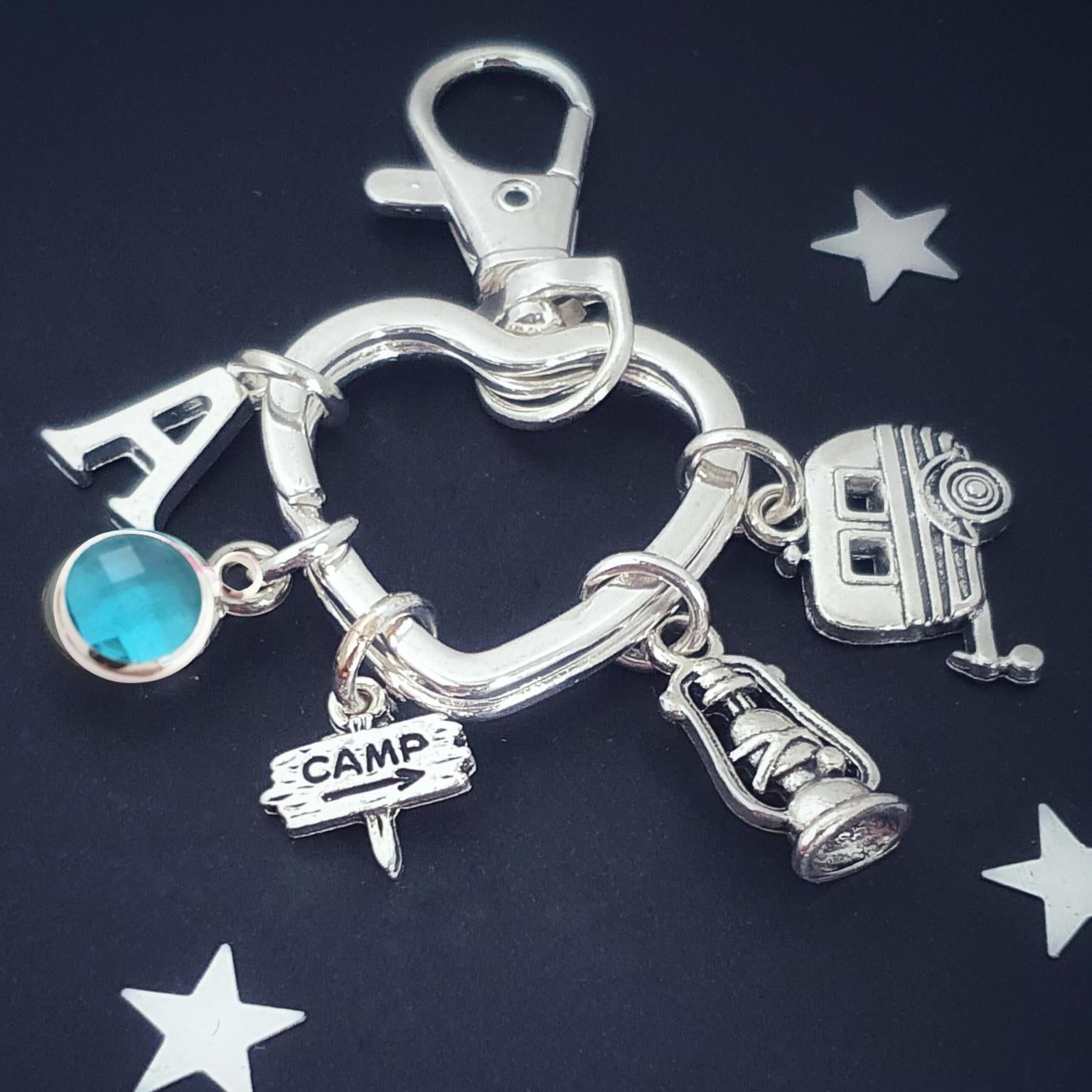 Silver keychain with various camping charms on a dark background with star shapes