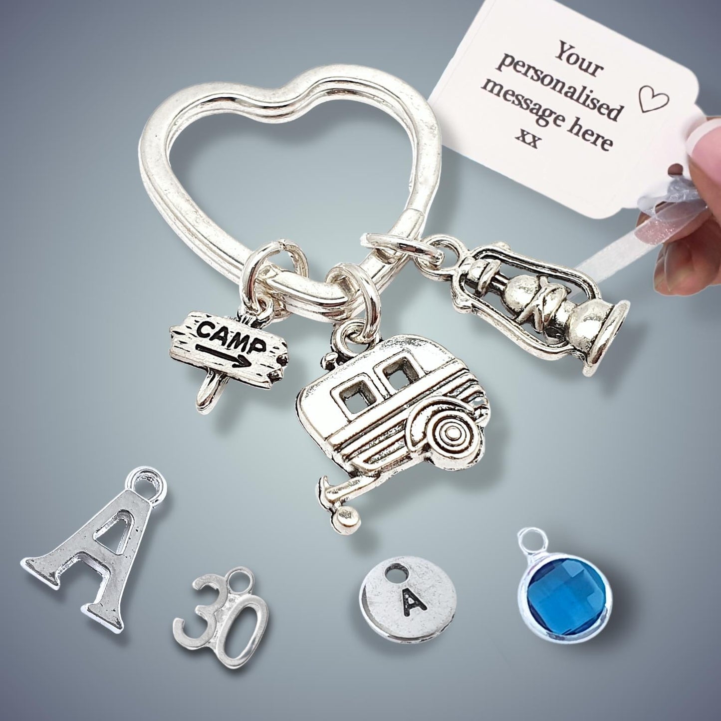 Silver keychain with various camping charms on a gray background