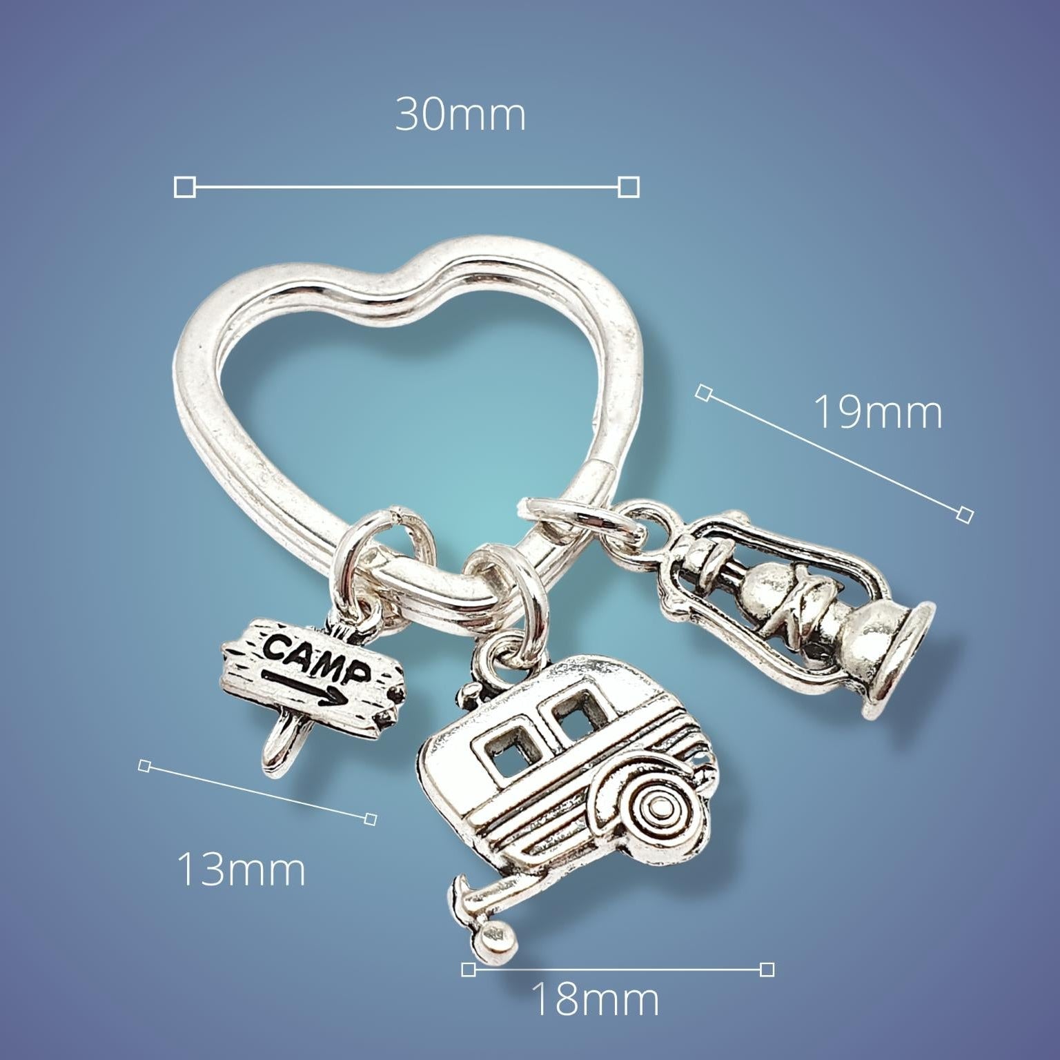Silver heart-shaped keychain with camping-themed charms on a blue background