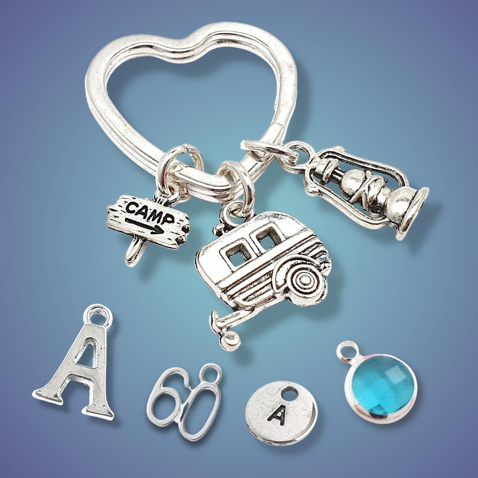 Silver keychain with various camping charms on a gradient blue background