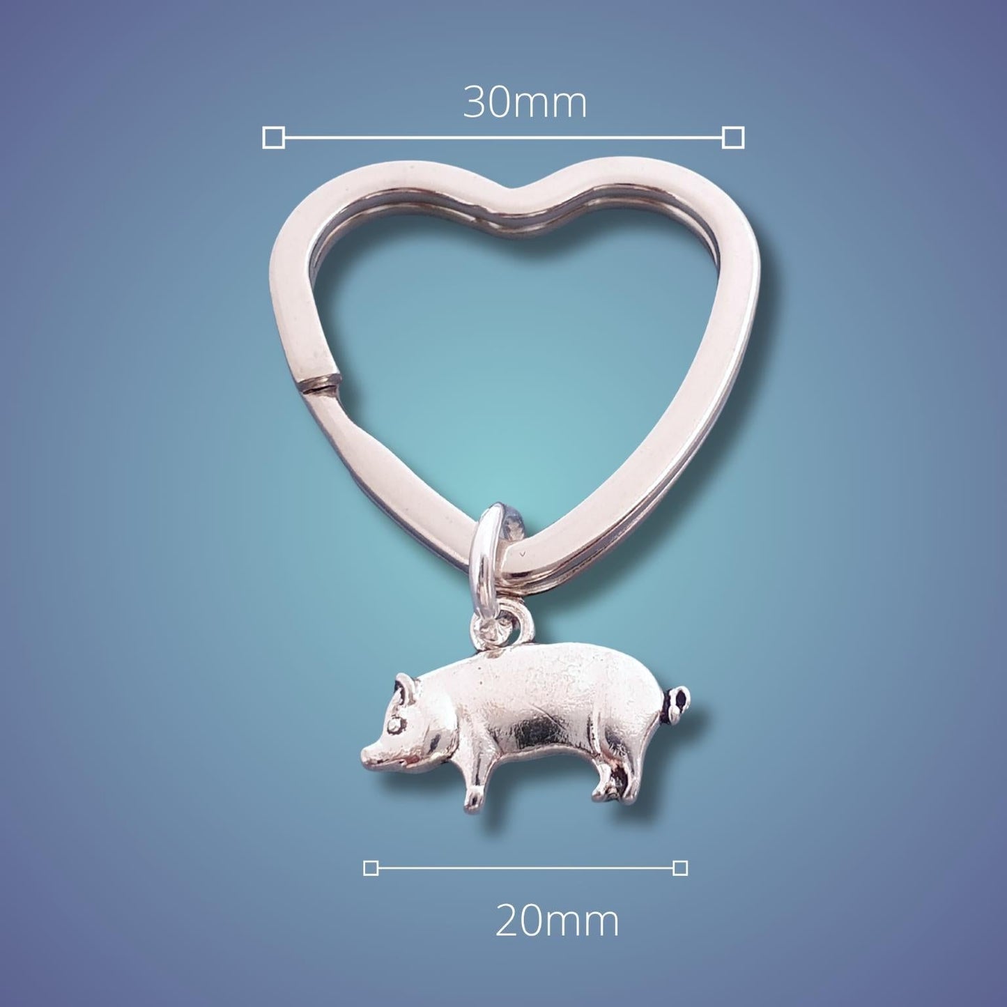 Silver heart-shaped keychain with a pig charm on a blue gradient background