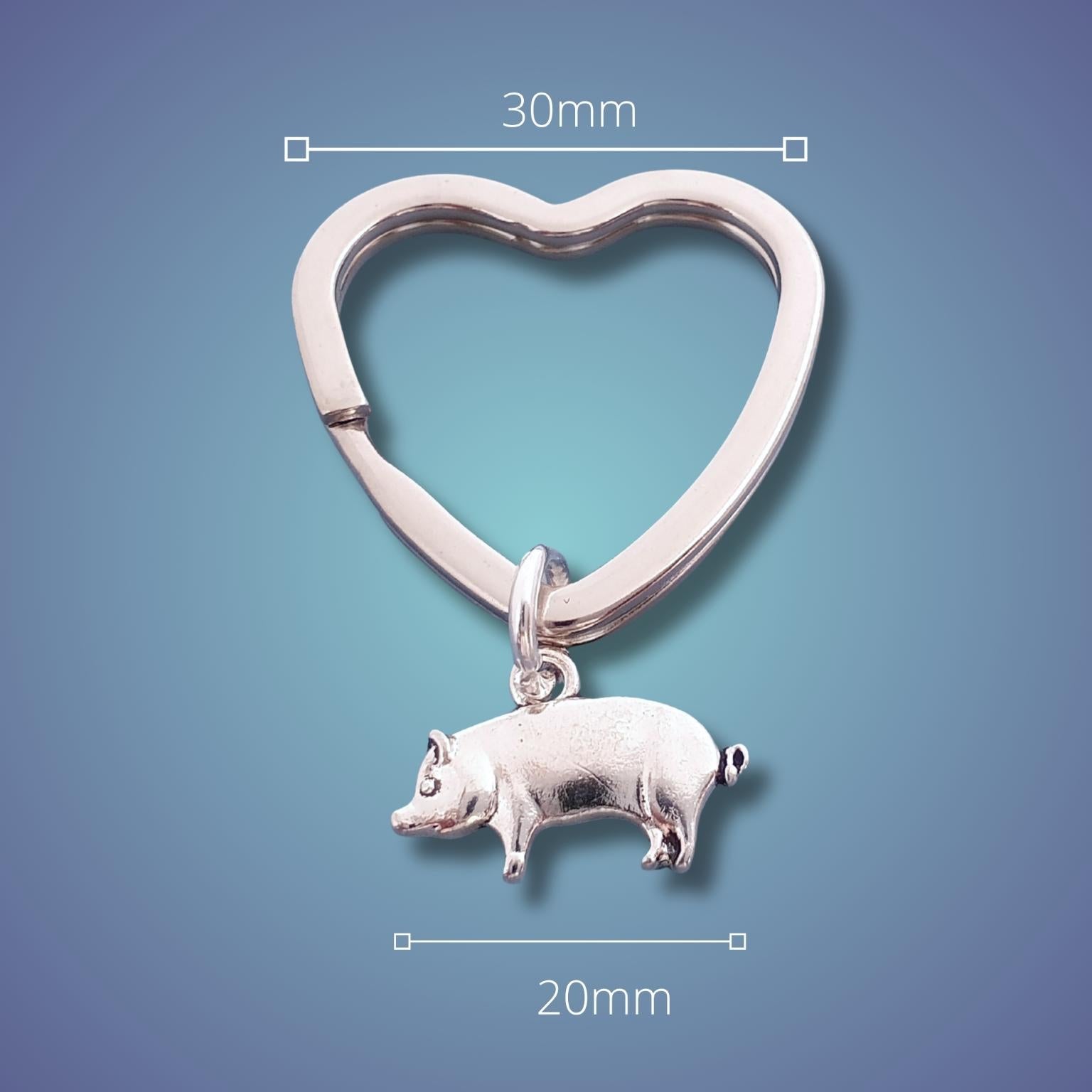 Silver heart-shaped keychain with a pig charm on a blue gradient background