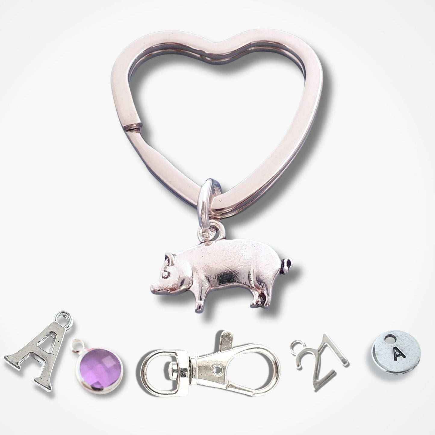 Heart-shaped keychain with pig charm and additional charms on a white background
