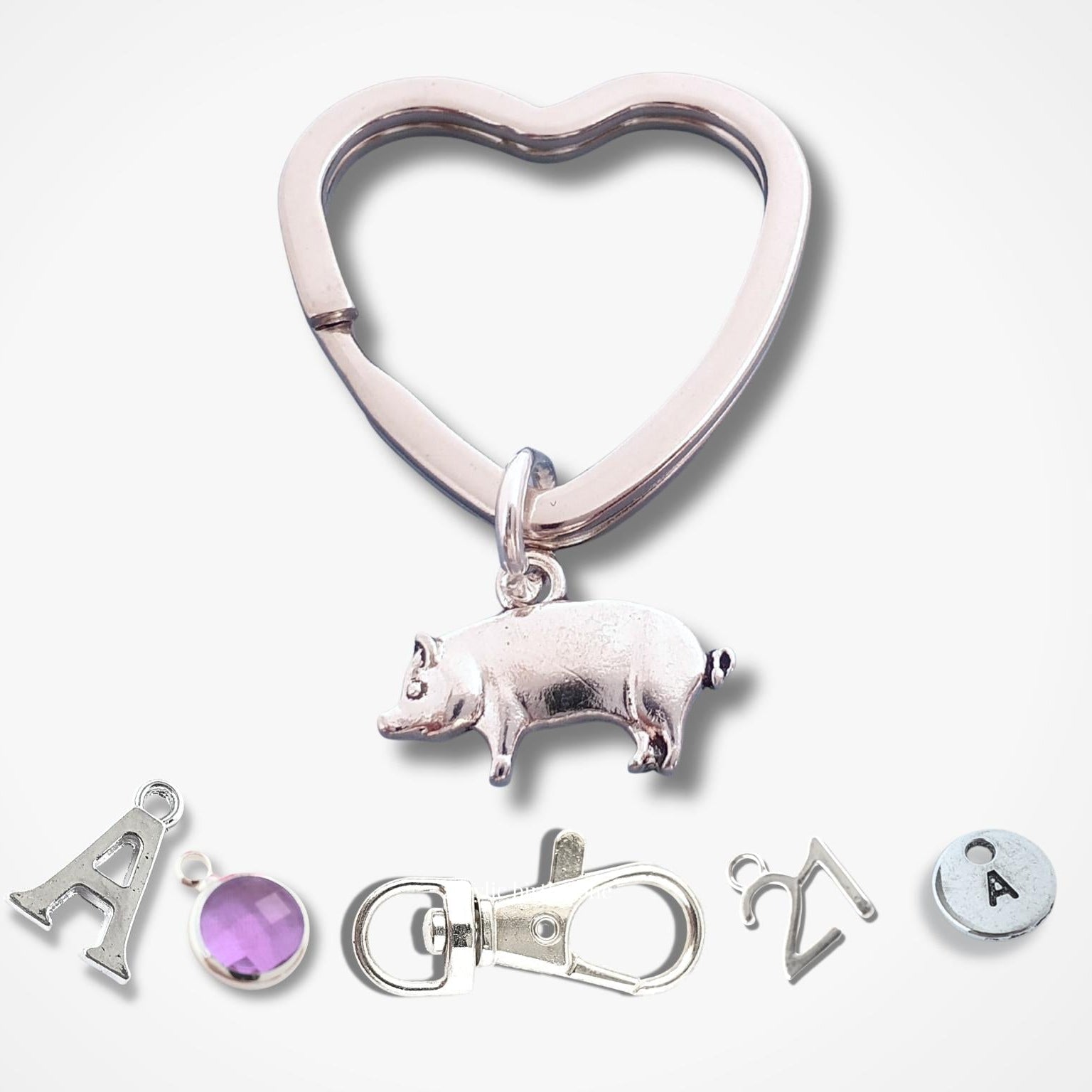Heart-shaped keychain with pig charm and additional charms on a white background
