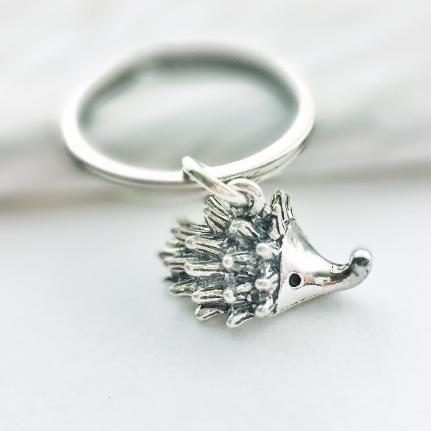 Silver hedgehog keychain on a white background