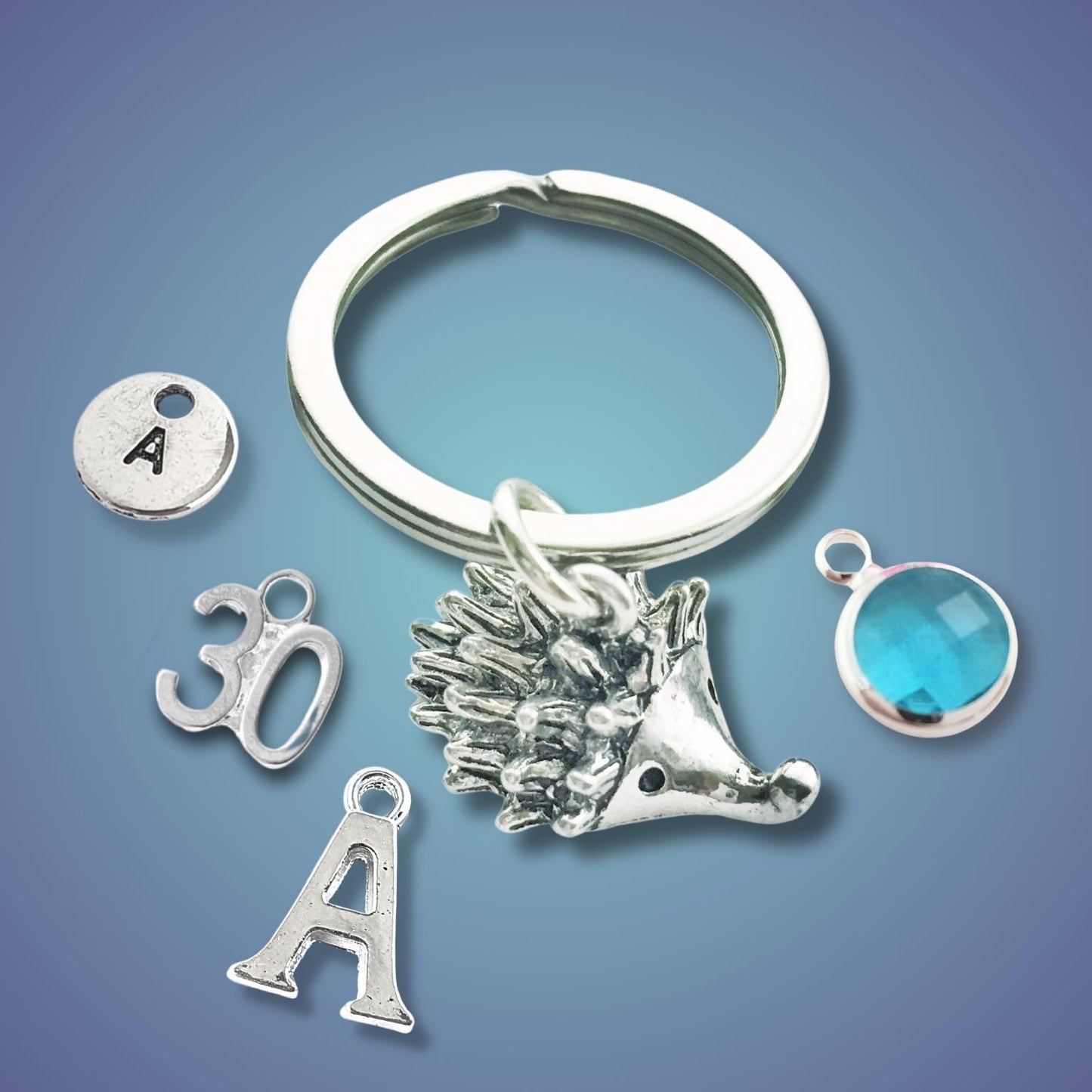 Silver keychain with hedgehog charm and other charms on a blue gradient background