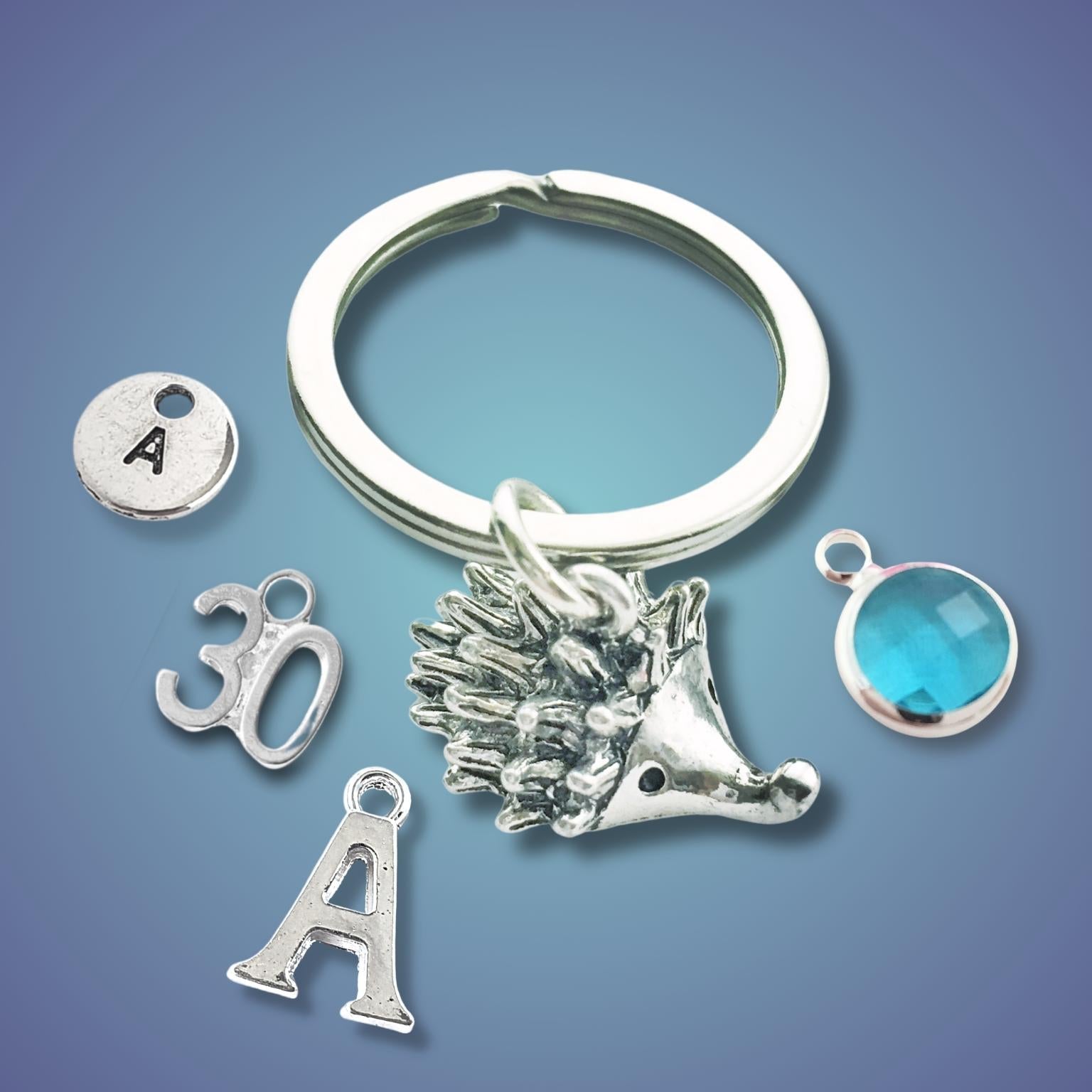 Silver keychain with hedgehog charm and other charms on a blue gradient background