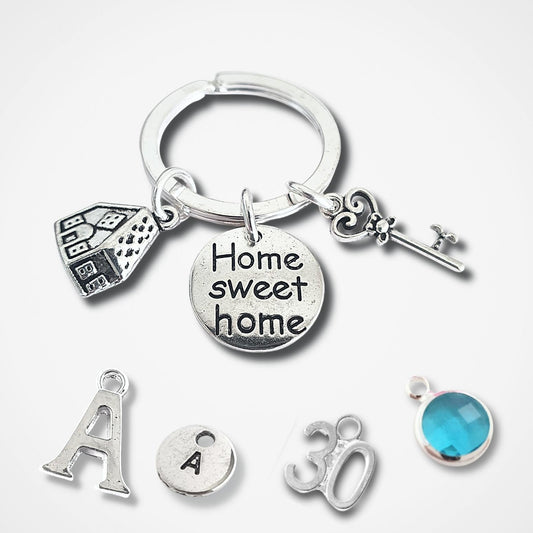 Silver keychain with various charms including a house, key, and 'Home sweet home' tag on a white background.