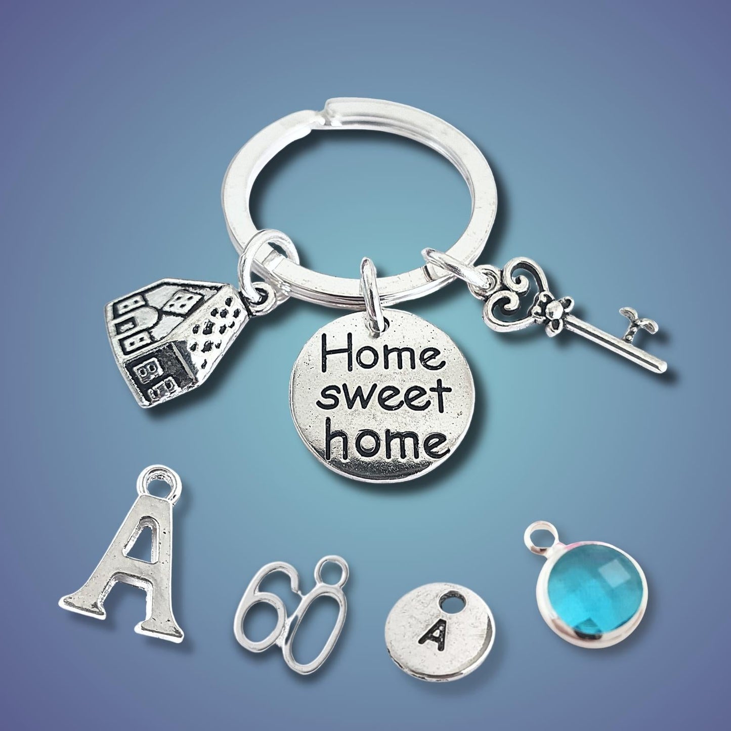 Silver keychain with various charms including a house, key, and 'Home sweet home' tag on a blue gradient background.