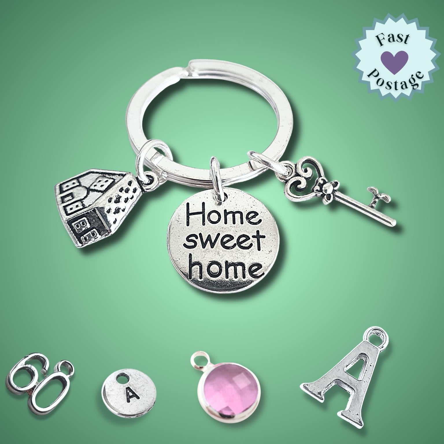 Silver keychain with 'Home sweet home' charm and additional charms on a green background