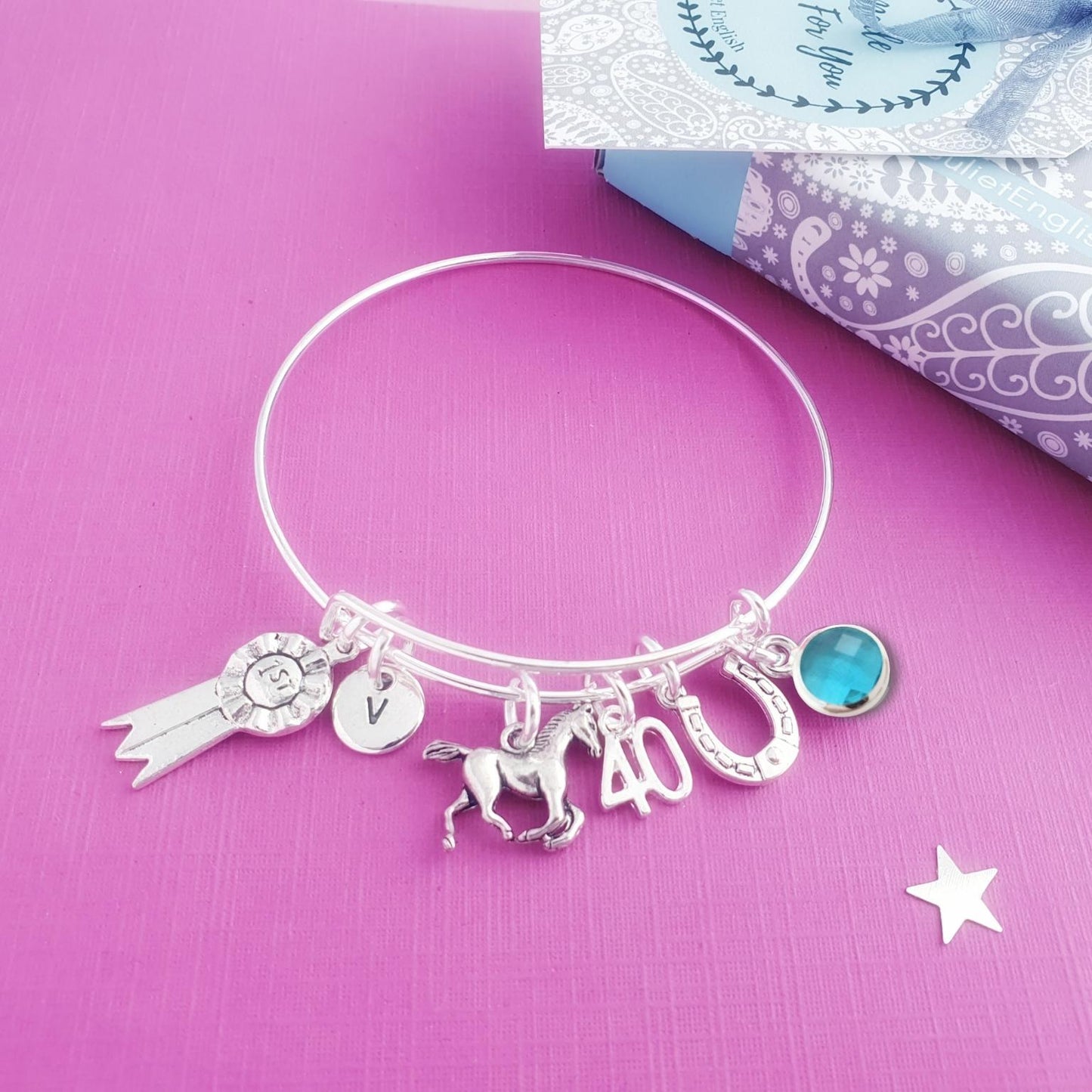 Silver bracelet with horse charms on a pink background