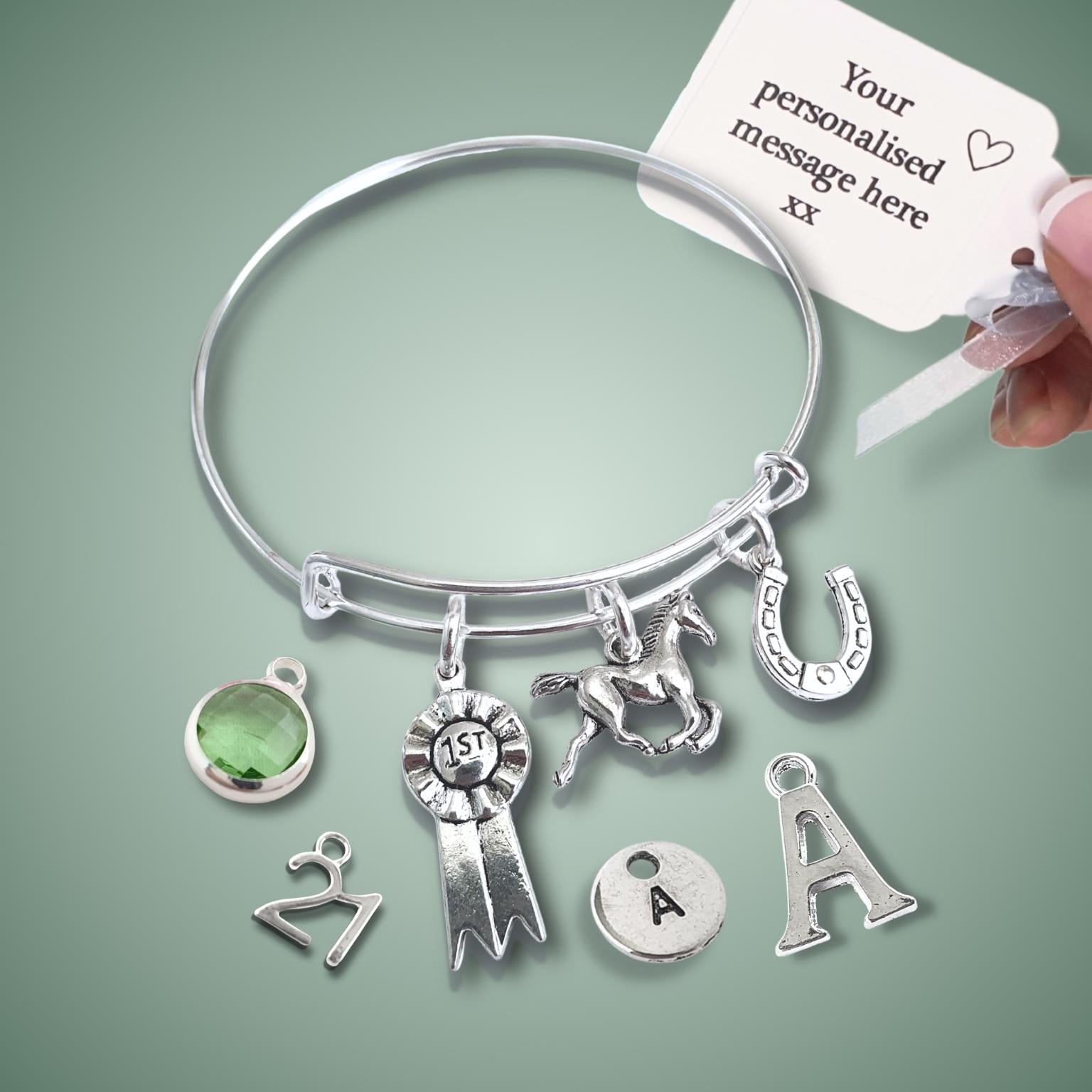 Silver bracelet with horse charms and a personalized message card on a green background