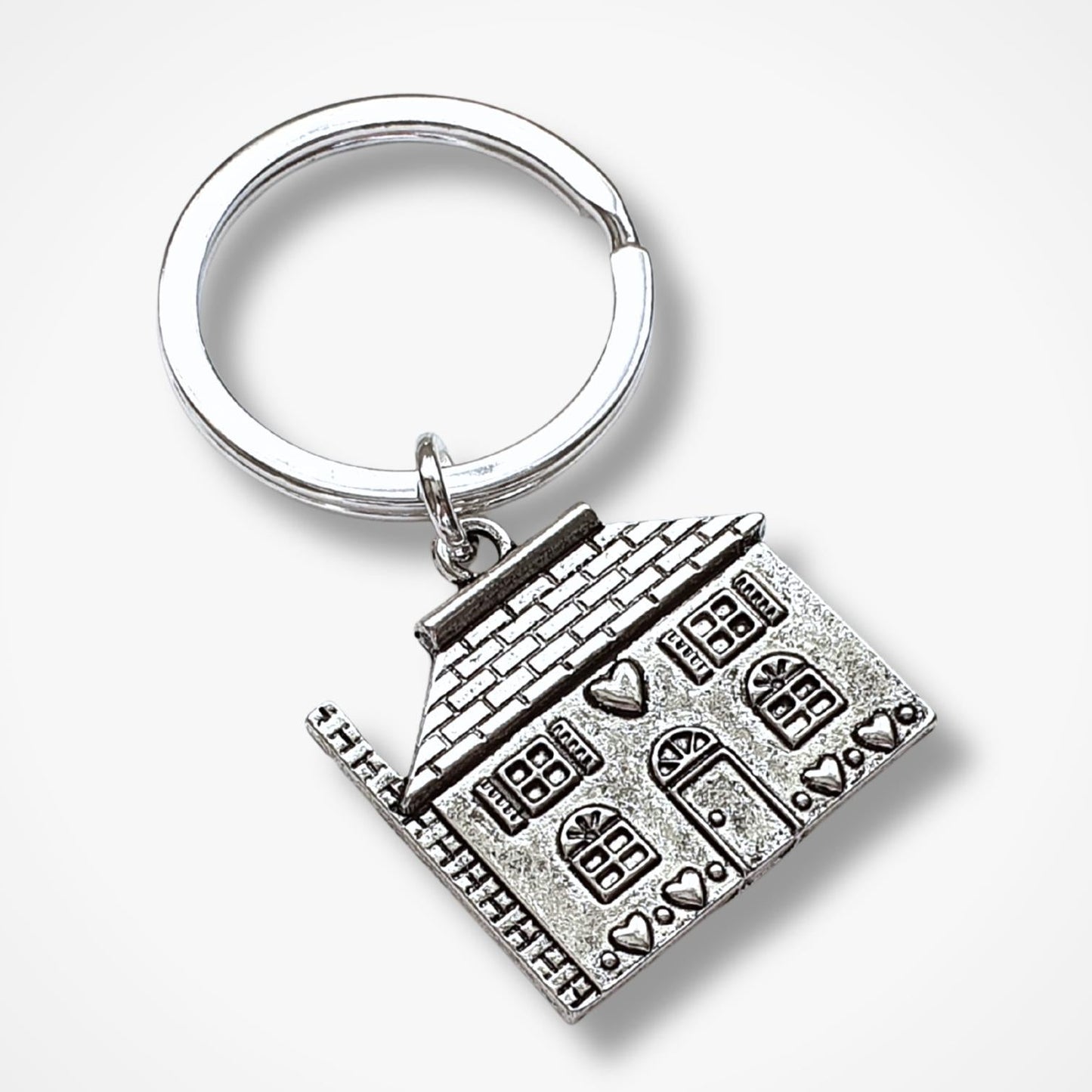 Silver keychain with a detailed house design on a white background