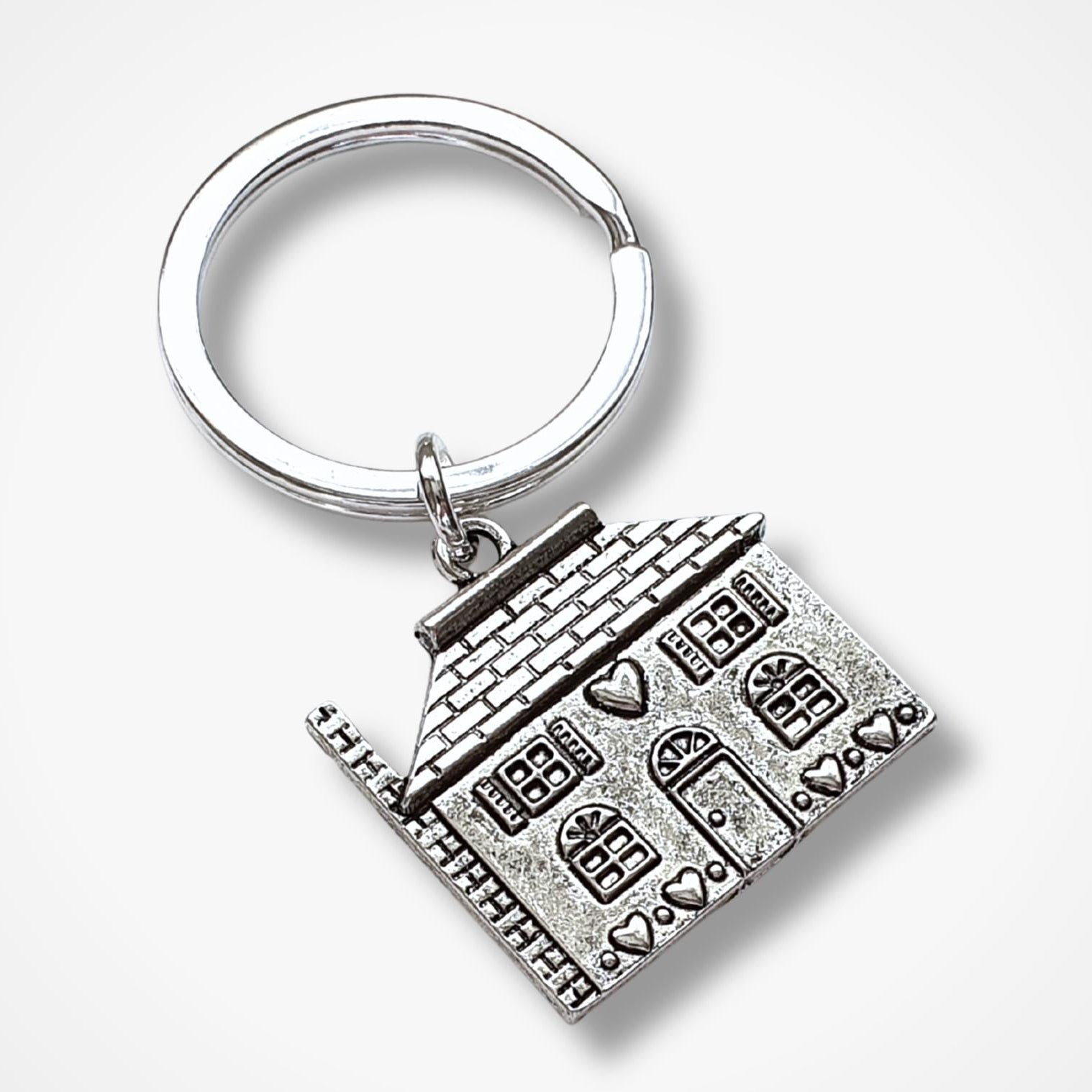 Silver keychain with a detailed house design on a white background