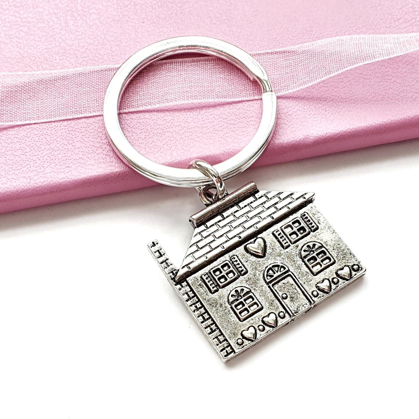 Silver house-shaped keychain on a pink ribbon