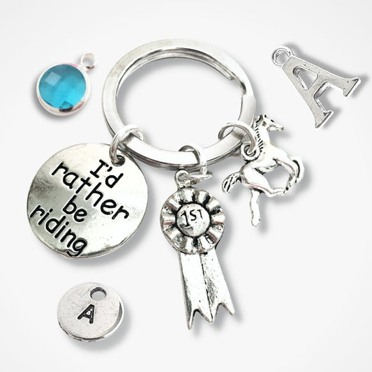 Silver keychain with various charms including a horse, letter 'A', and 'I'd rather be riding' tag.