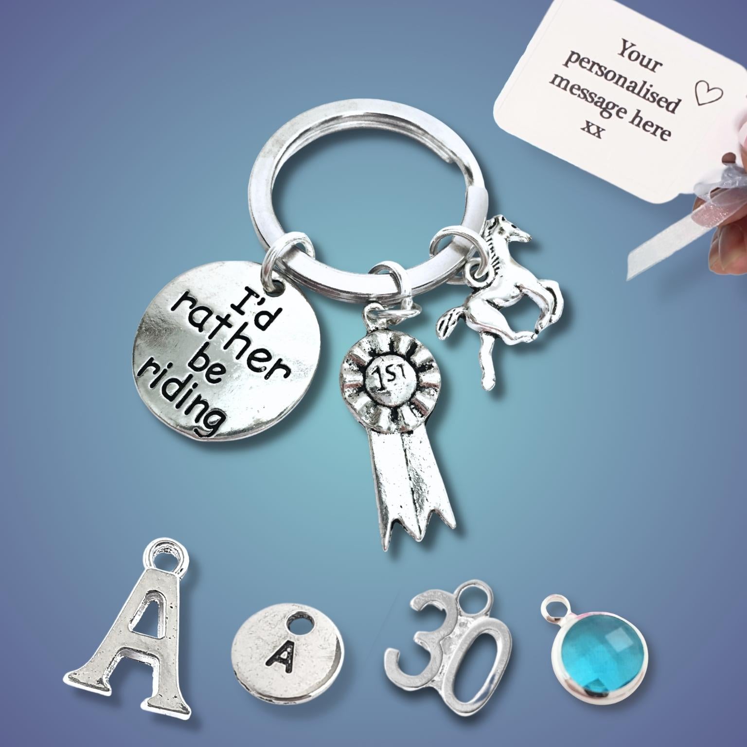 Silver keychain with various charms including a horse and 'I'd rather be riding' tag and a customizable message card on a blue background