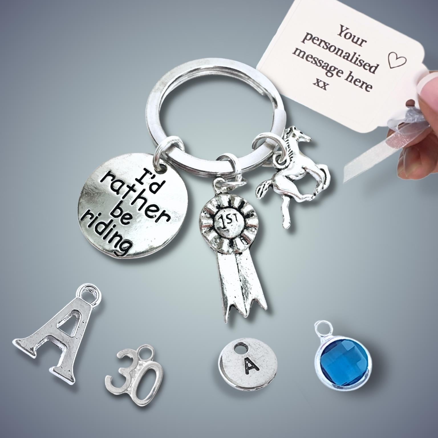 Silver keychain with various charms including a horse and 'I'd rather be riding' tag and a hand holding a card with text on a gray background