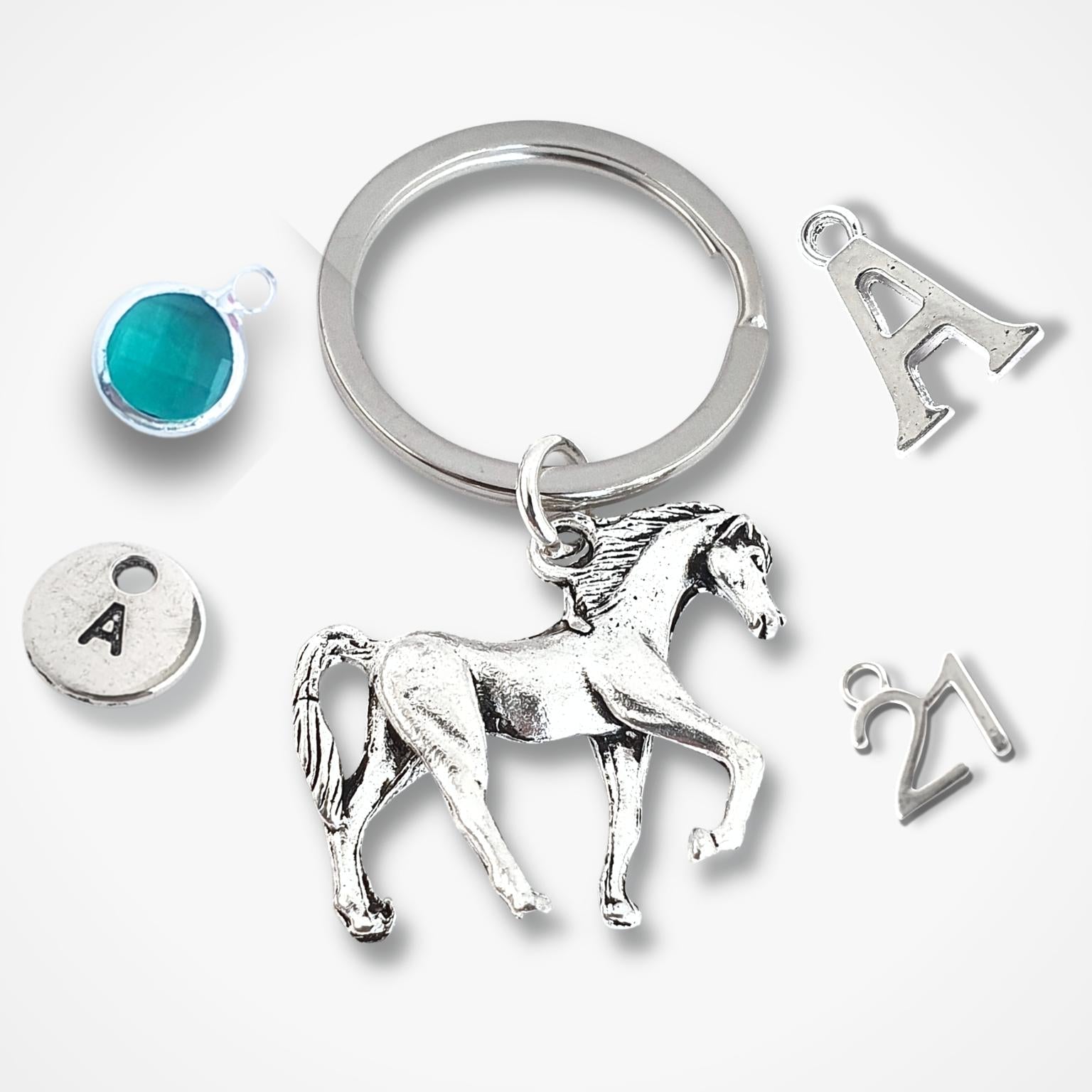 Silver keychain with horse charm and other small charms on a white background