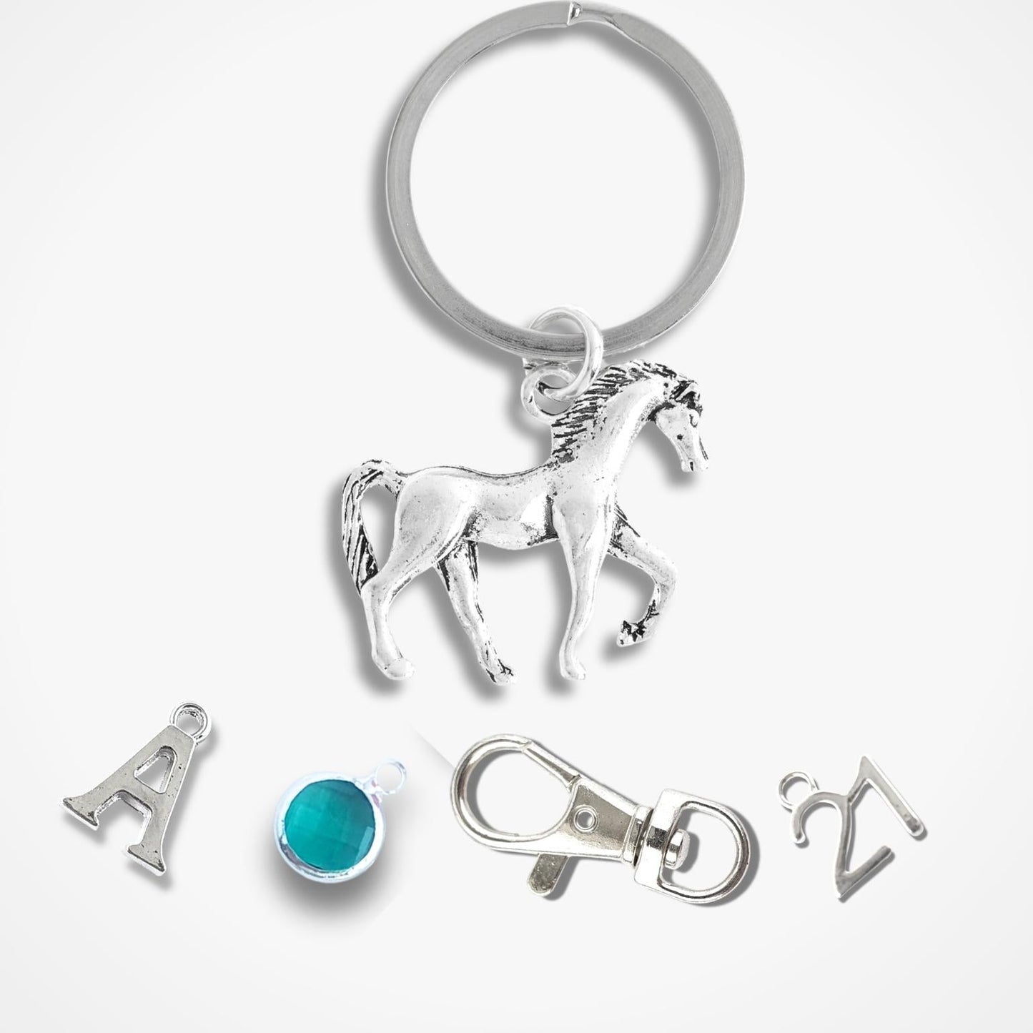 Silver keychain with horse charm and additional charms on a white background