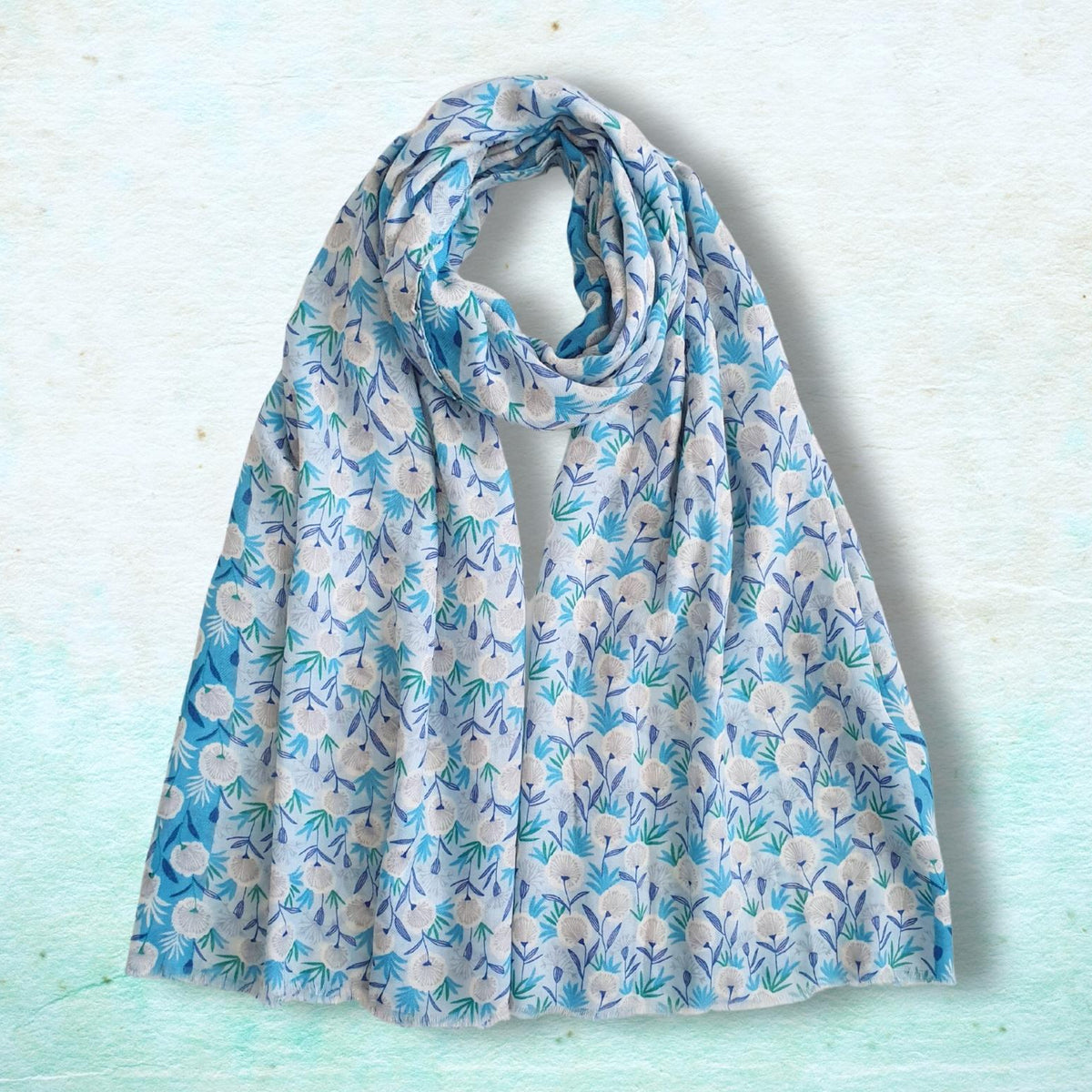 A medium weight scarf with a blue and white floral pattern, draped in a loop to showcase its soft drape and pattern, set against a textured light blue background.