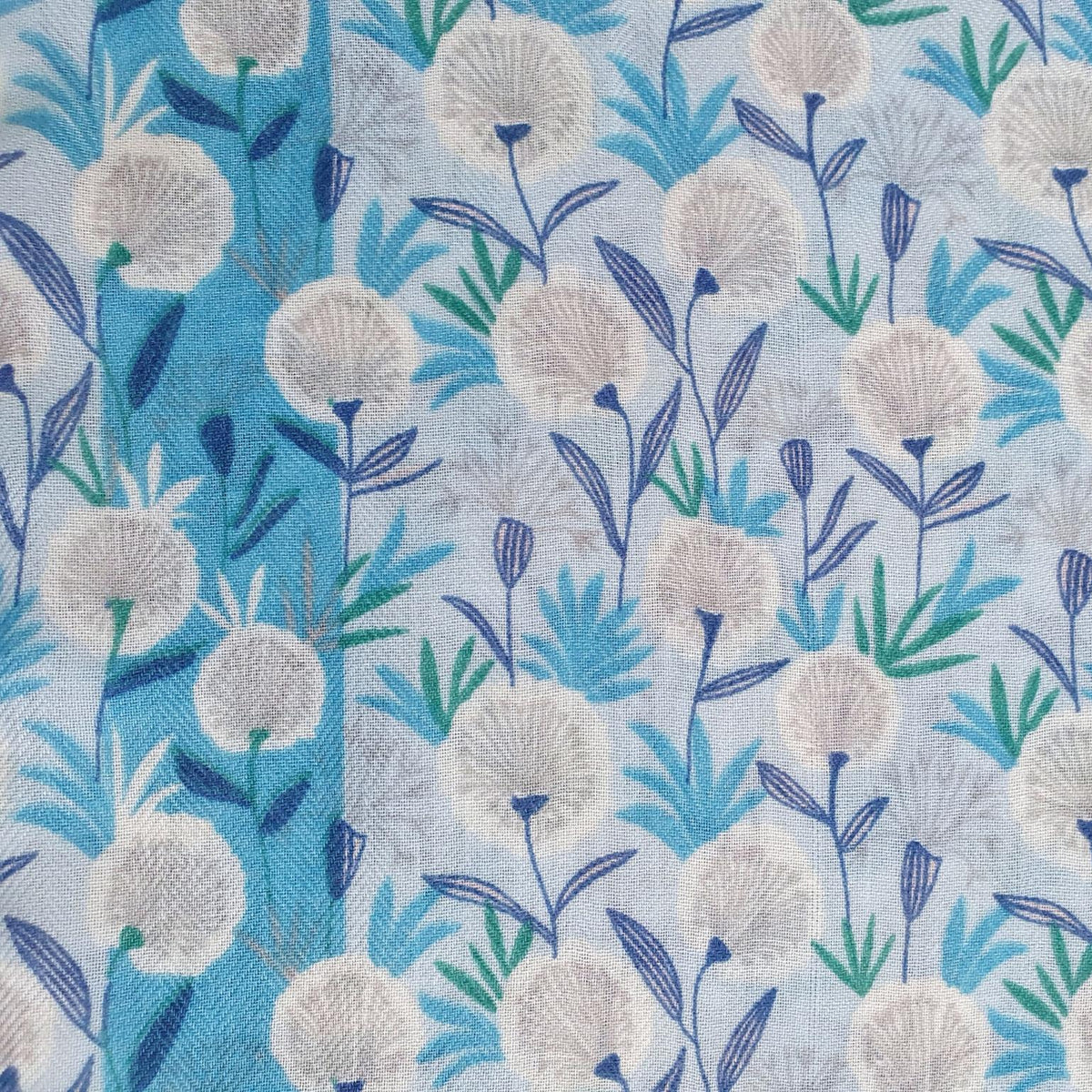 A close-up of a fabric pattern featuring white dandelion-like flowers with blue and green stems and leaves on a light blue background.