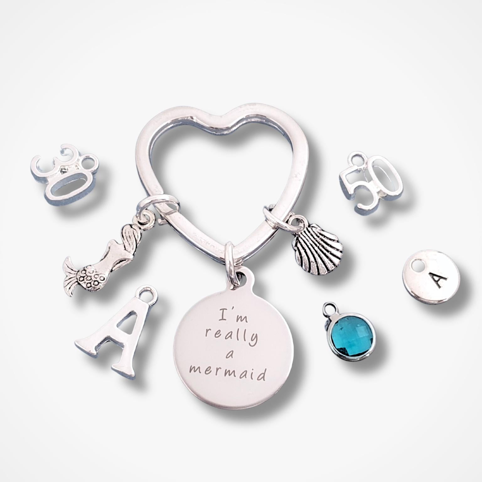 Keychain with various charms including a heart-shaped keyring, 'I'm really a mermaid' charm, and other decorative elements on a white background.