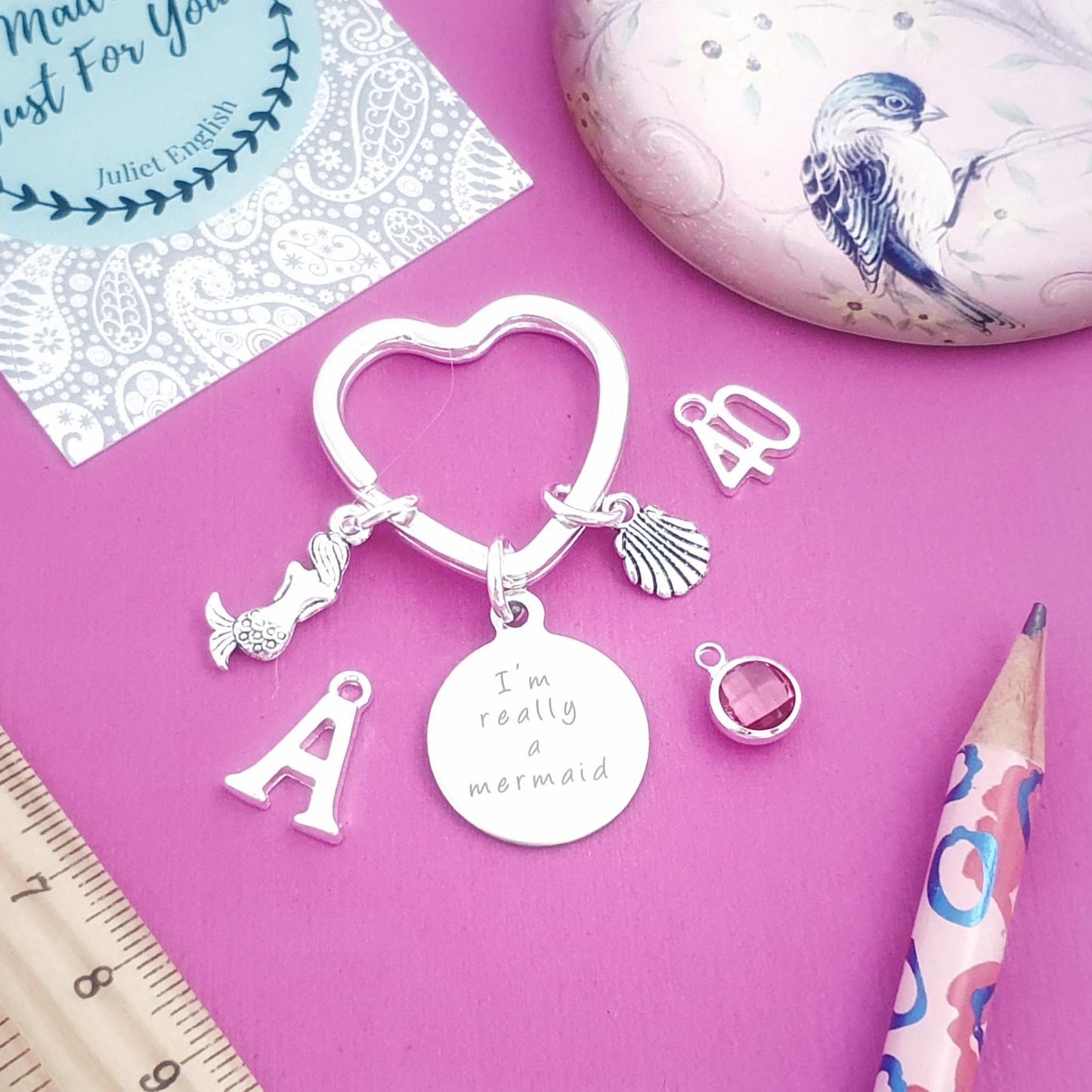Silver keychain with charms on a pink surface with stationery items