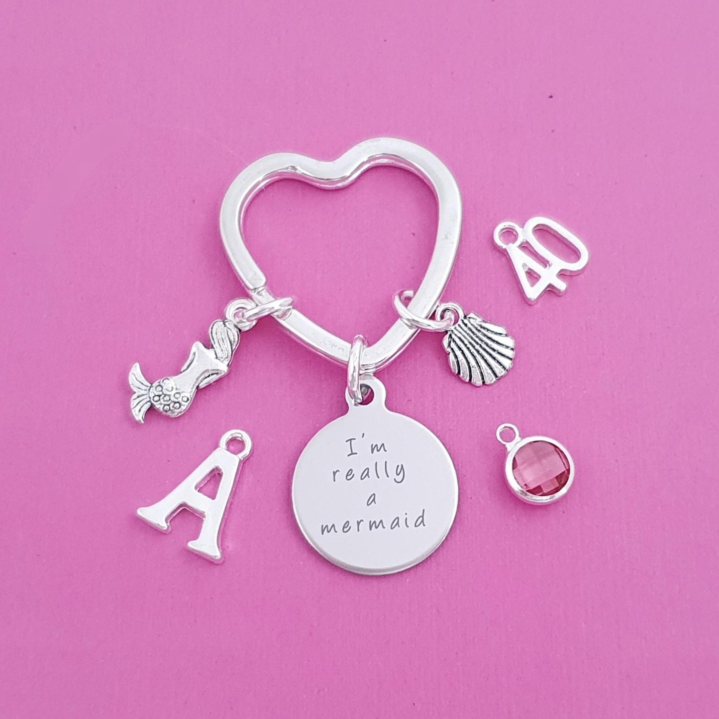 Silver keychain with charms on a pink background