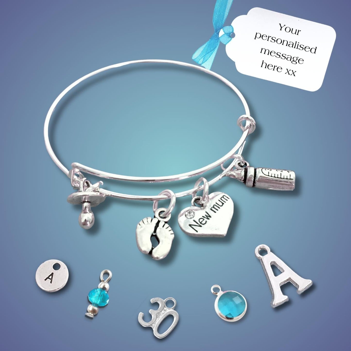 A silver bangle bracelet with multiple charms, including a baby bottle, footprint, heart, and letter charms, displayed on a blue gradient background with a white tag that reads 'Your personalised message here xx'.