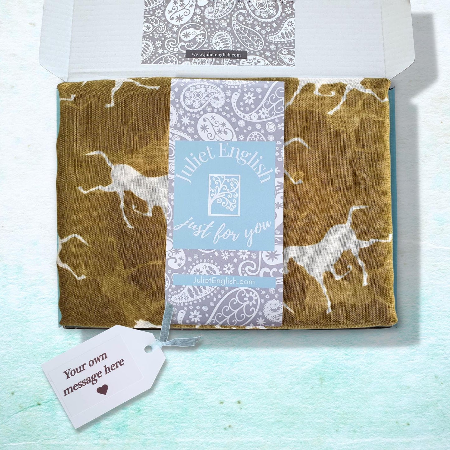 A gift box with a custom printed insert card and a hanging tag, featuring a patterned scarf with horse motifs.
