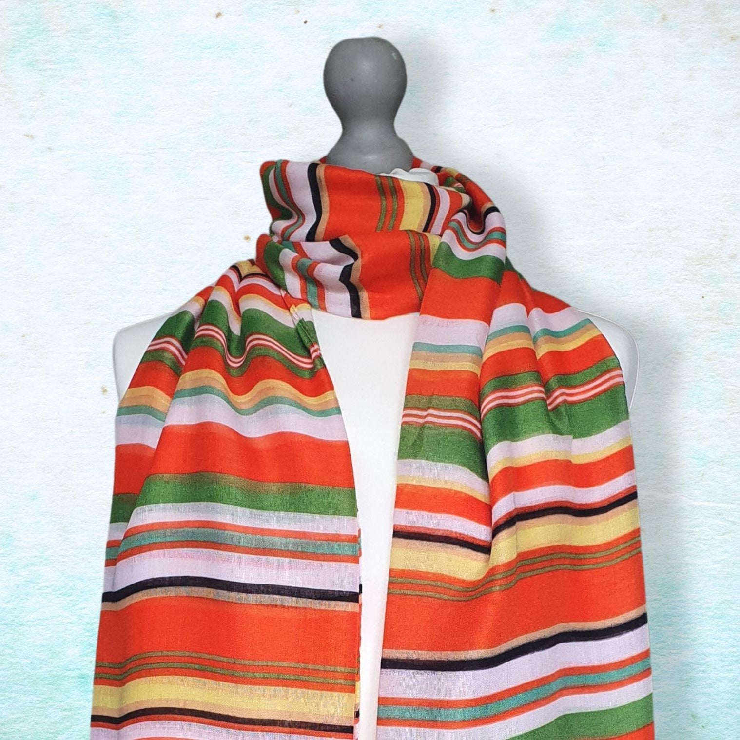 Colorful striped scarf on a mannequin against a light blue background