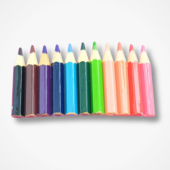 Hairslide with set of colorful pencils arranged in a row on a light gray background
