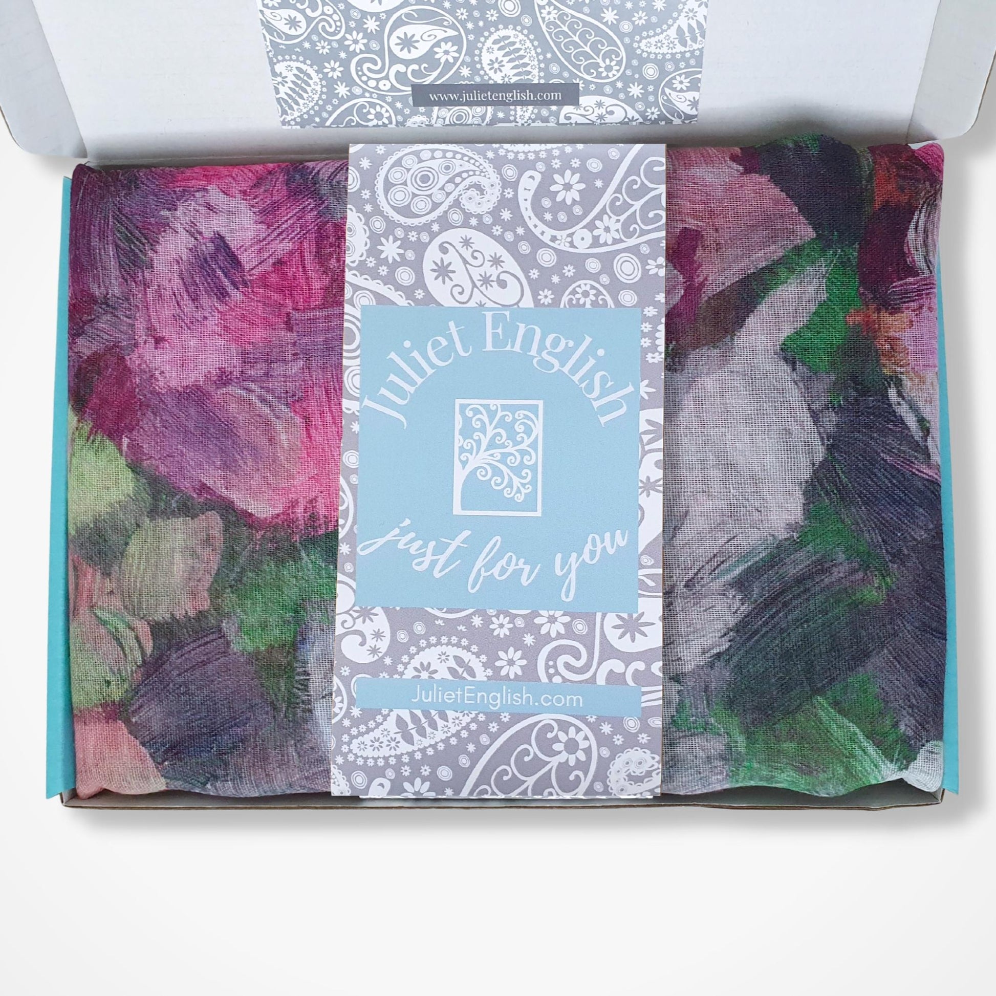 Gift box with folded scarf with a visible brand label on a white background