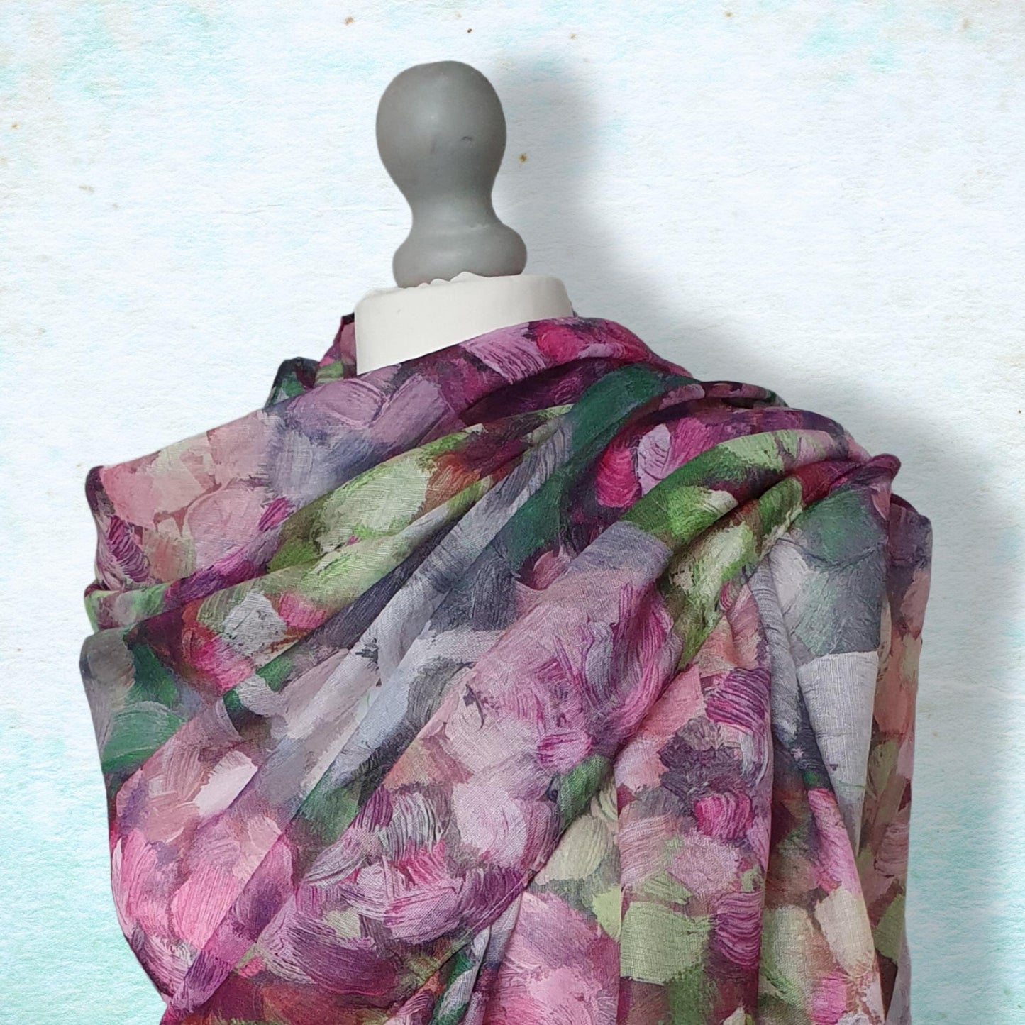 Multicolored floral scarf on a mannequin against a light blue background