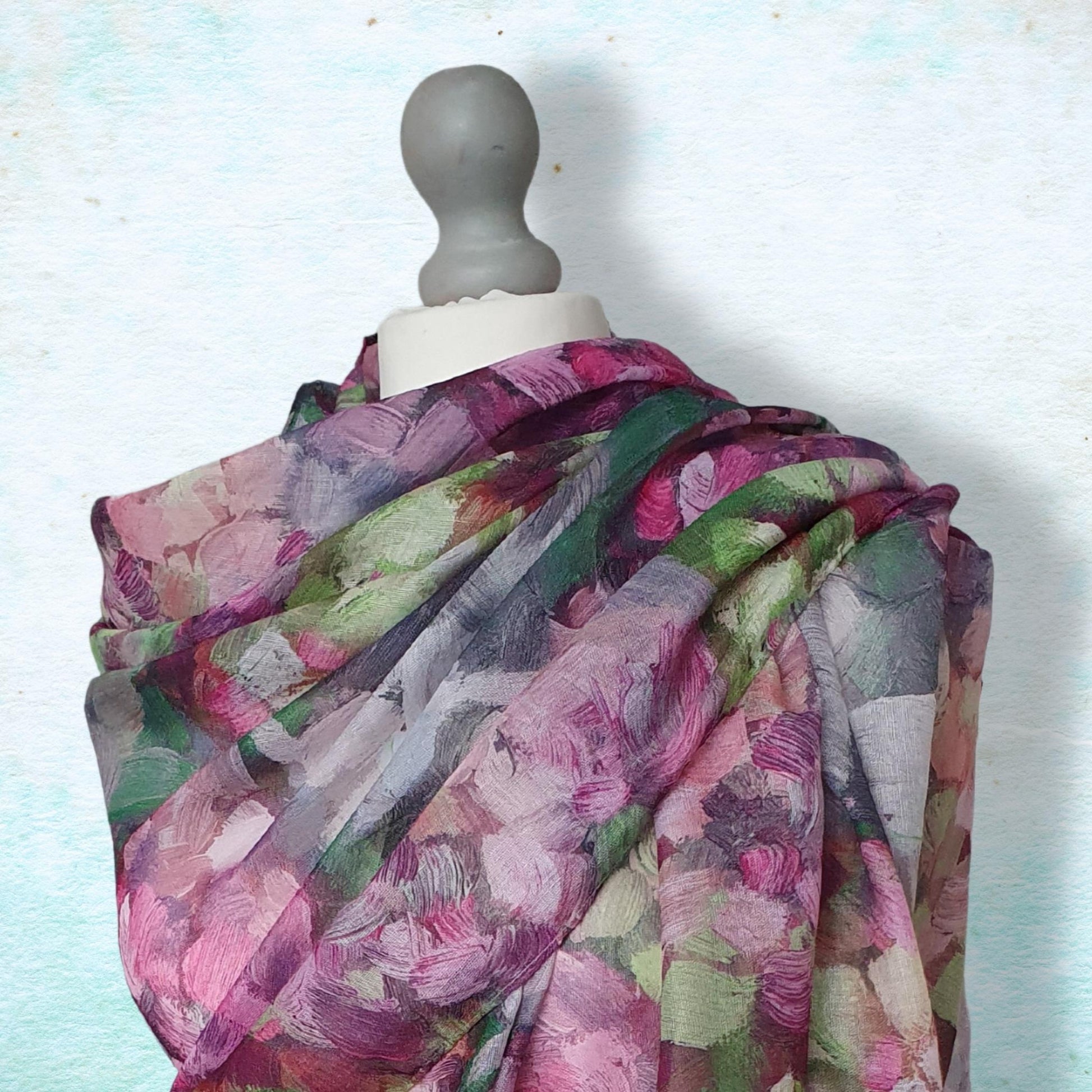 Multicolored floral scarf on a mannequin against a light blue background
