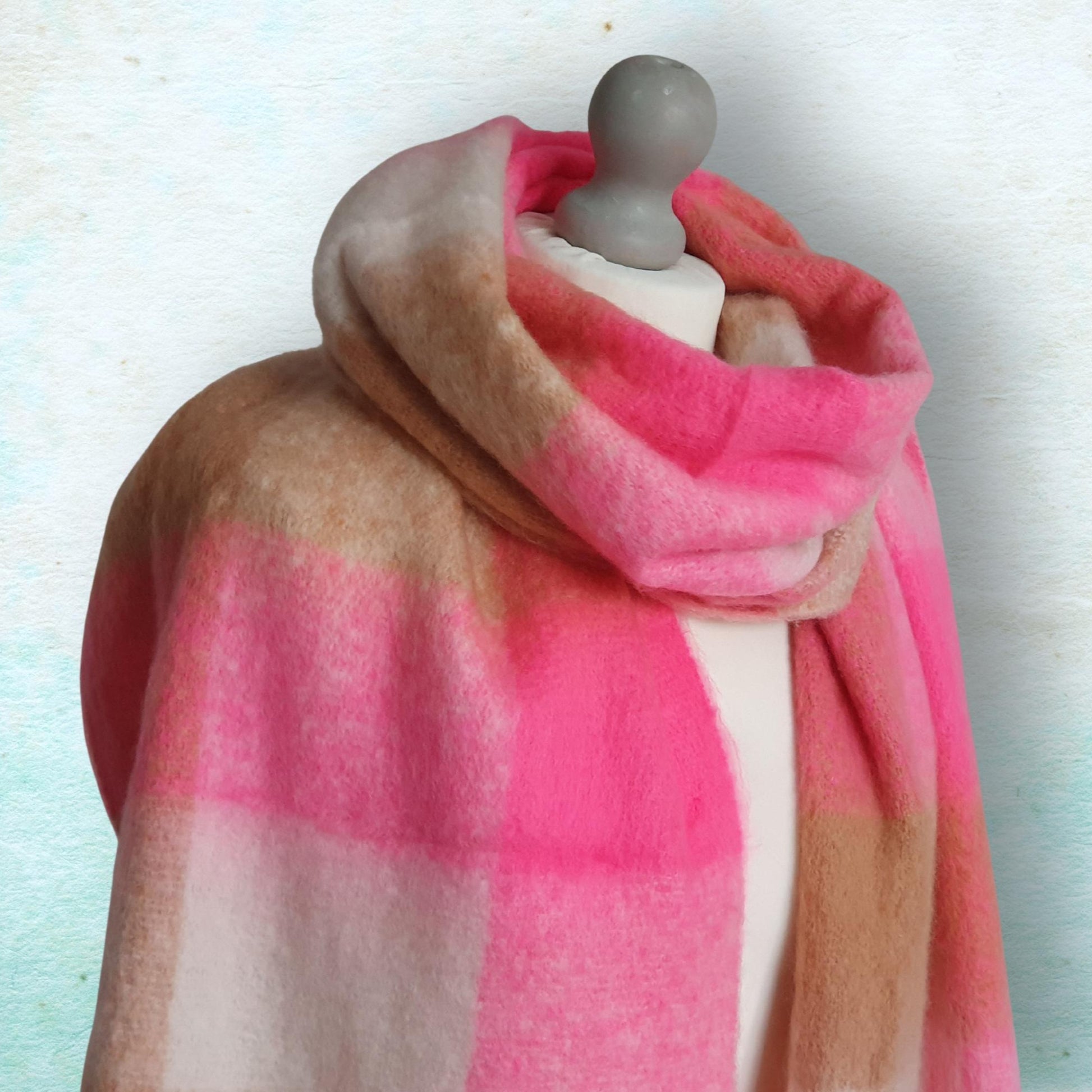 Mannequin wearing a pink and brown plaid scarf against a light background