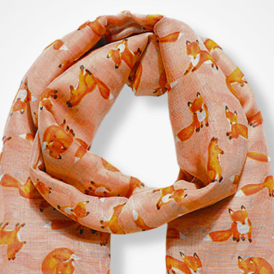 A peach-colored scarf with an all-over print of cartoon foxes in orange, white, and black, arranged in a loop against a plain white background.