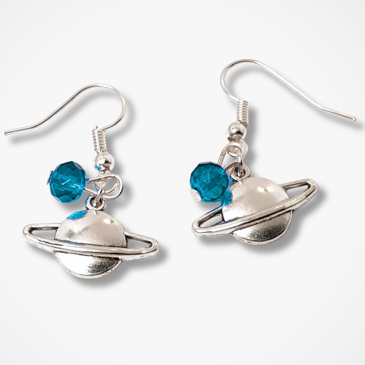 Silver Saturn-themed earrings with blue beads on a white background