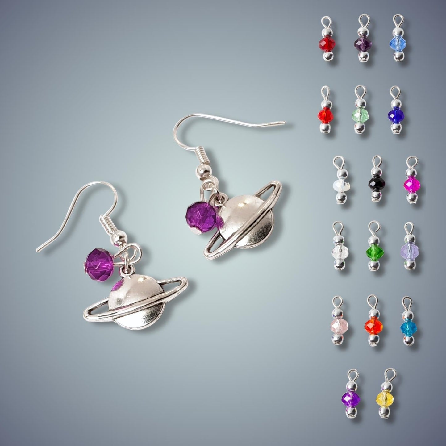 Saturn-themed earrings with colorful beads on a gray background