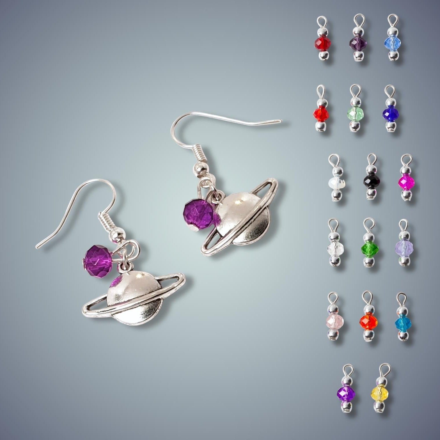 Saturn-themed earrings with colorful beads on a gray background