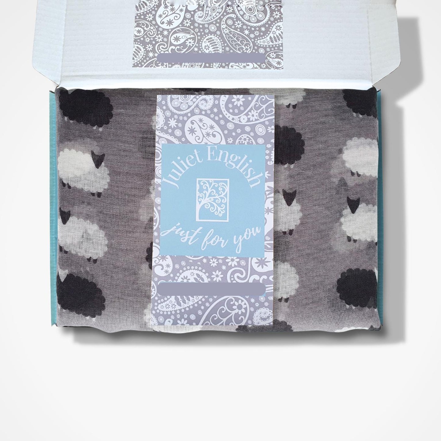 Scarf with sheep pattern in a branded box on a white background