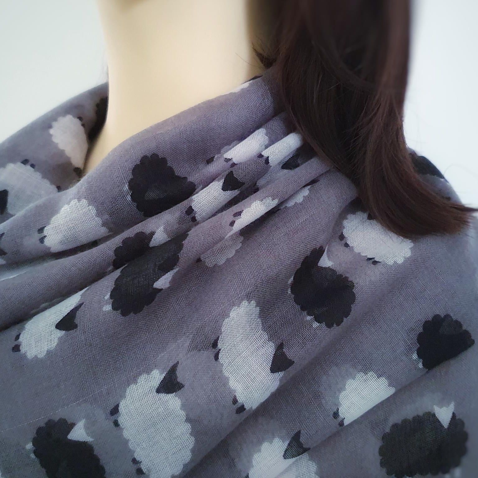 Person wearing a gray scarf with black and white sheep pattern