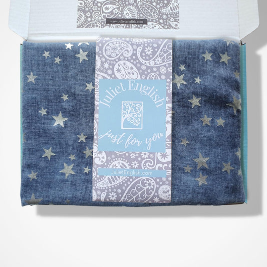 A folded blue with metallic silver stars patterned scarf, presented inside an open box. 