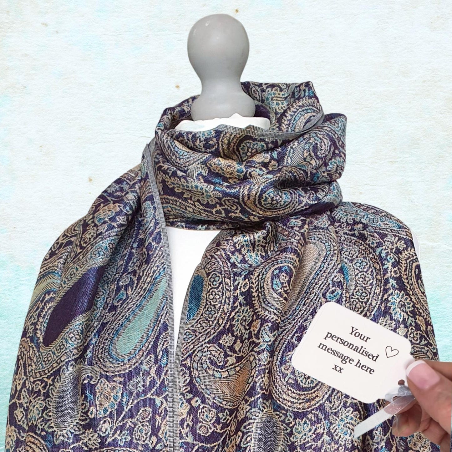 Patterned scarf on a mannequin with a customizable tag against a light blue background
