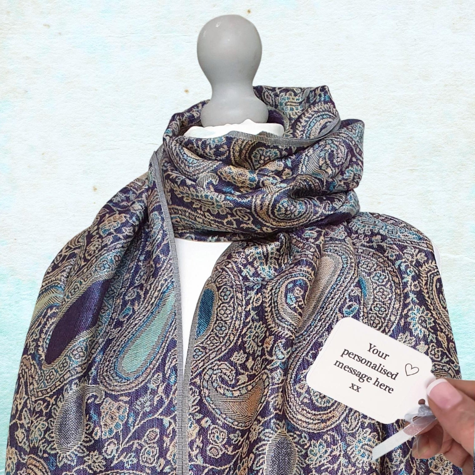 Patterned scarf on a mannequin with a customizable tag against a light blue background