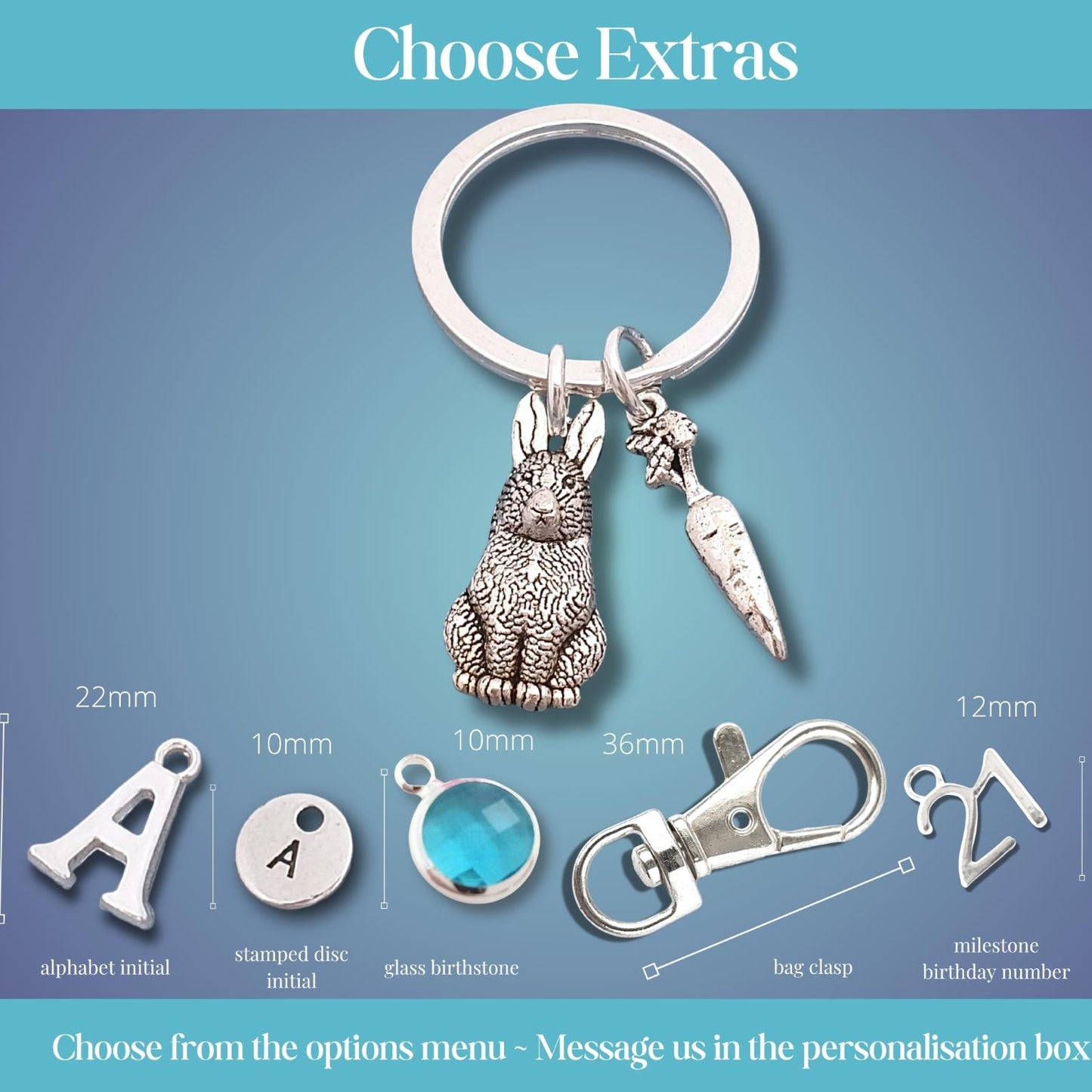 Personalized keychain customization options displayed on a blue gradient background, featuring a silver metal key ring with a rabbit and carrot charm, plus size and detail callouts for alphabet initial, stamped disc initial, glass birthstone, bag clip, and milestone birthday number extras.